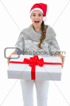 Surprised woman in Santa hat holding big Christmas present