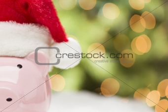Pink Piggy Bank Wearing Red and White Santa Hat on Snowflakes with Abstract Green and Golden Background - Room for Your Own Text.
