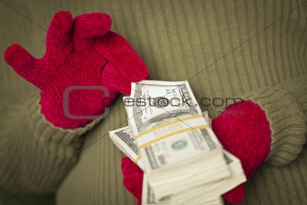 Woman Wearing Red Mittens and Green Sweater Holding Stacks of Hundreds of Dollars of Money with Red Ribbon.