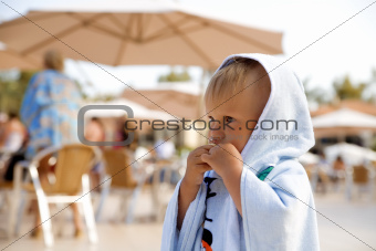 little boy is wrapped in towel stands in surroundings people