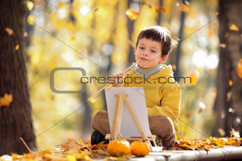 Cute little boy painting with brush outdoors in park on beautiful autumn day
