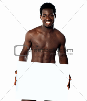 Young muscular man holding blank billboard