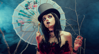 Attractive gothic girl in top hat with Chinese umbrella looking 