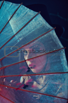 Attractive gothic lady in top hat looking through Chinese umbrel
