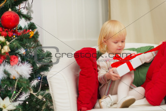 Baby sitting on chair and open Christmas present box
