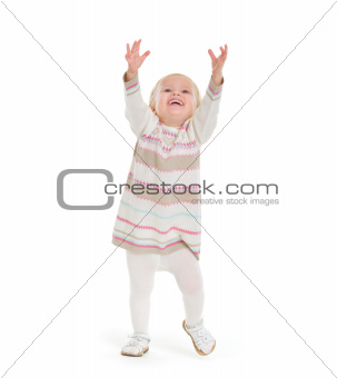 Baby girl in knit winter clothing pulling up to get something