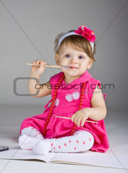 Seated little girl holding a paintbrush