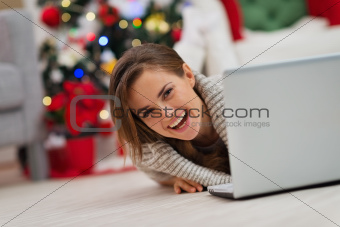 Smiling woman looking out from laptop in front of Christmas tree