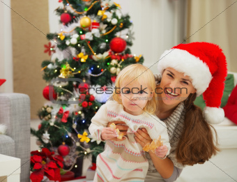 Portrait of mother and eat smeared baby near Christmas tree