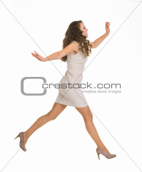 Young woman in dress jumping. Side view