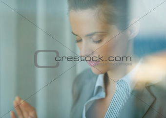 Portrait of thoughtful business woman leaning on window
