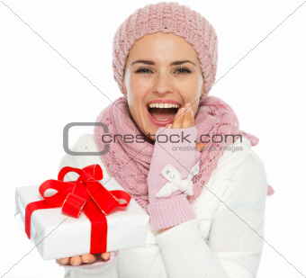 Surprised young woman in knit winter clothing holding Christmas present box
