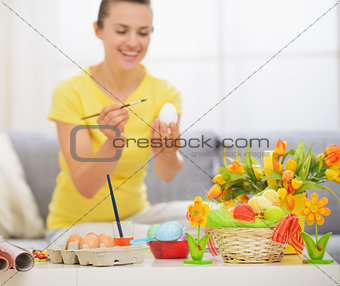 Closeup on table with Easter decoration and woman drawing on egg