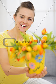 Happy young woman showing bouquet of tulips in bucket