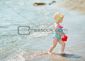 Baby playing with pail on seashore