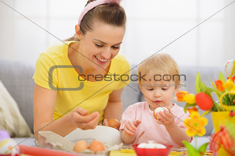 Happy mother and baby eating Easter eggs