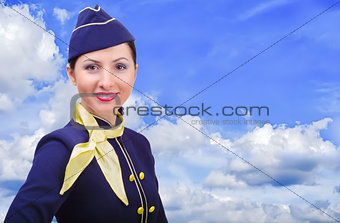 Beautiful young  smiling stewardess in uniform on a background sky