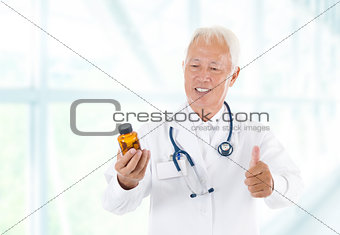 Thumb up Asian doctor holding bottle pills