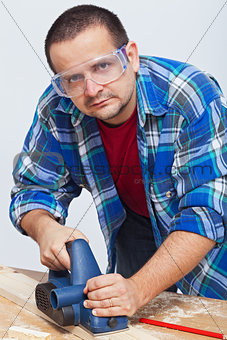 Man working wood with an electric planer