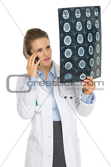 Medical doctor woman speaking cell phone and looking on MRI