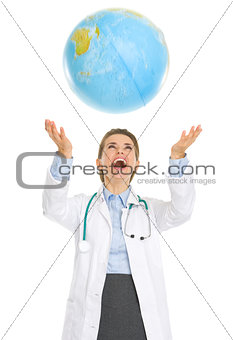 Happy medical doctor woman throws up globe