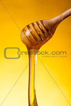 Close-up shot of wooden drizzler and flowing honey 