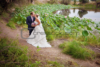 kissing bride and groom near lotos pond