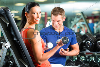 woman and Personal Trainer in gym with dumbbells