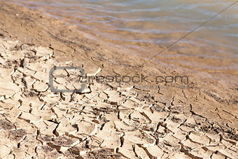 Contrast concept of dry cracked mud next to water