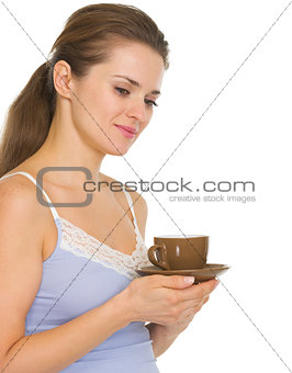 Thoughtful young woman in pajamas after sleep with cup of coffee