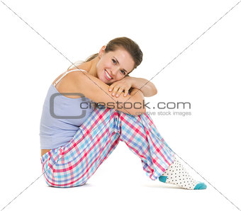 Happy young woman in pajamas sitting on floor isolated on white