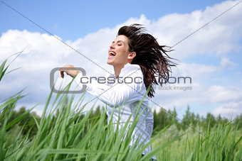 Woman with long hair running outside under blue sky in the field