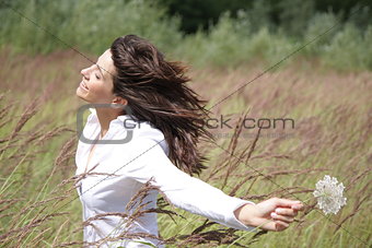 Beautiful woman outside, with wind in her face and a flower in h
