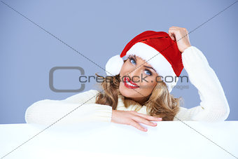 Woman in a santa hat resting on a blank billboard