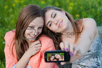 Two happy teenage girl friends and mobile