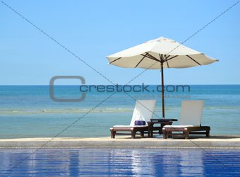 Two chairs and white umbrella on the beach