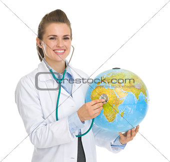 Happy medical doctor woman listening globe with stethoscope