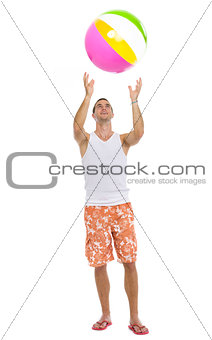 Full length portrait of young man playing with beach ball