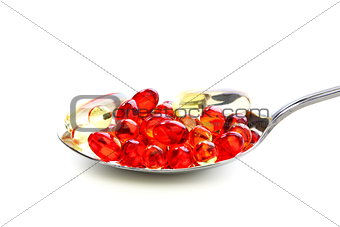 Colored capsules with vitamins in a spoonful.