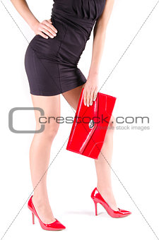 Slender beautiful womanish feet in red shoes and mini bag isolated