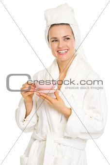 Smiling young woman in bathrobe with cup of coffee