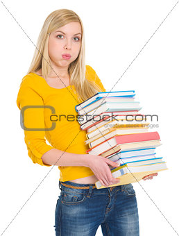 Tired student girl holding pile of books