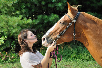 Young adult woman kissing her horse