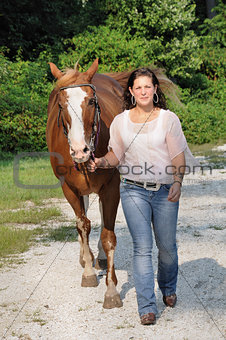 Young adult woman walking her horse