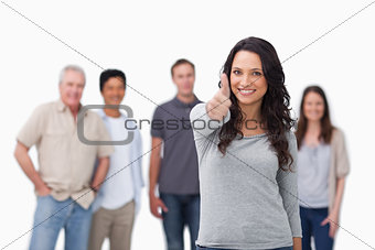 Smiling woman with friends behind her giving thumb up