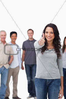 Smiling woman giving thumb up with friends behind her