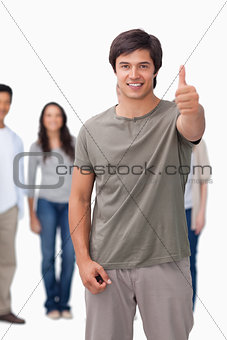 Smiling man giving thumb up with friends behind him