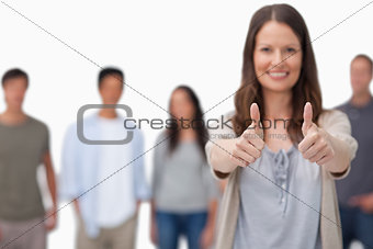 Thumbs up given by smiling woman with friends behind her