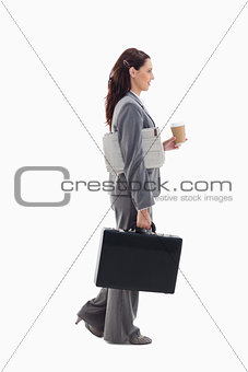 Profile of a businesswoman walking with a briefcase, newspaper a