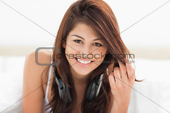 Woman looking straight ahead while smiling and clasping her hair